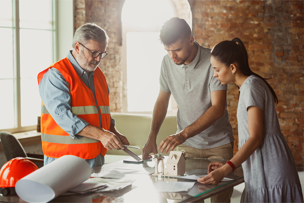 Couple discussing building plans and blueprints with a practitioner